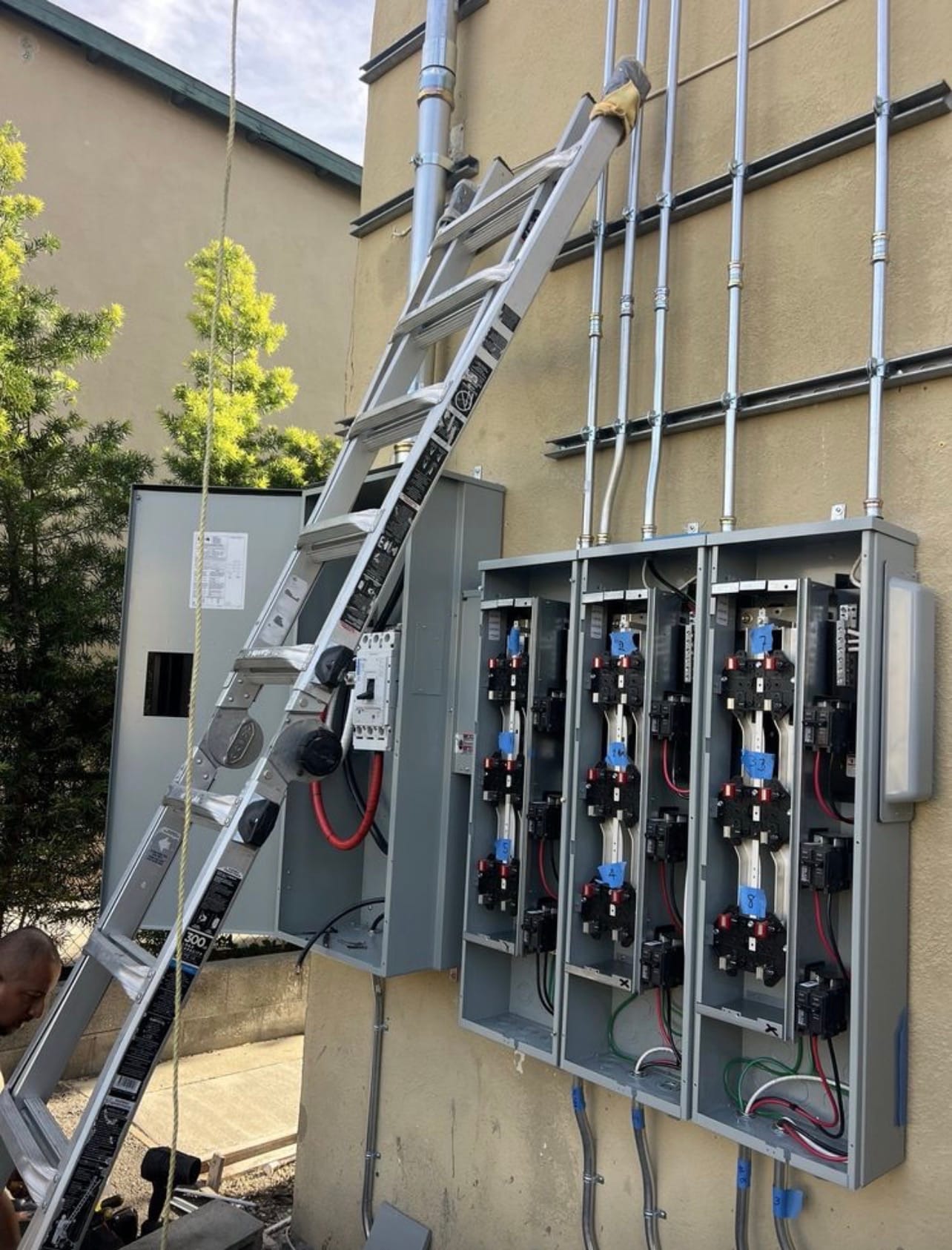 Meter bank upgrade on an exterior wall with a ladder