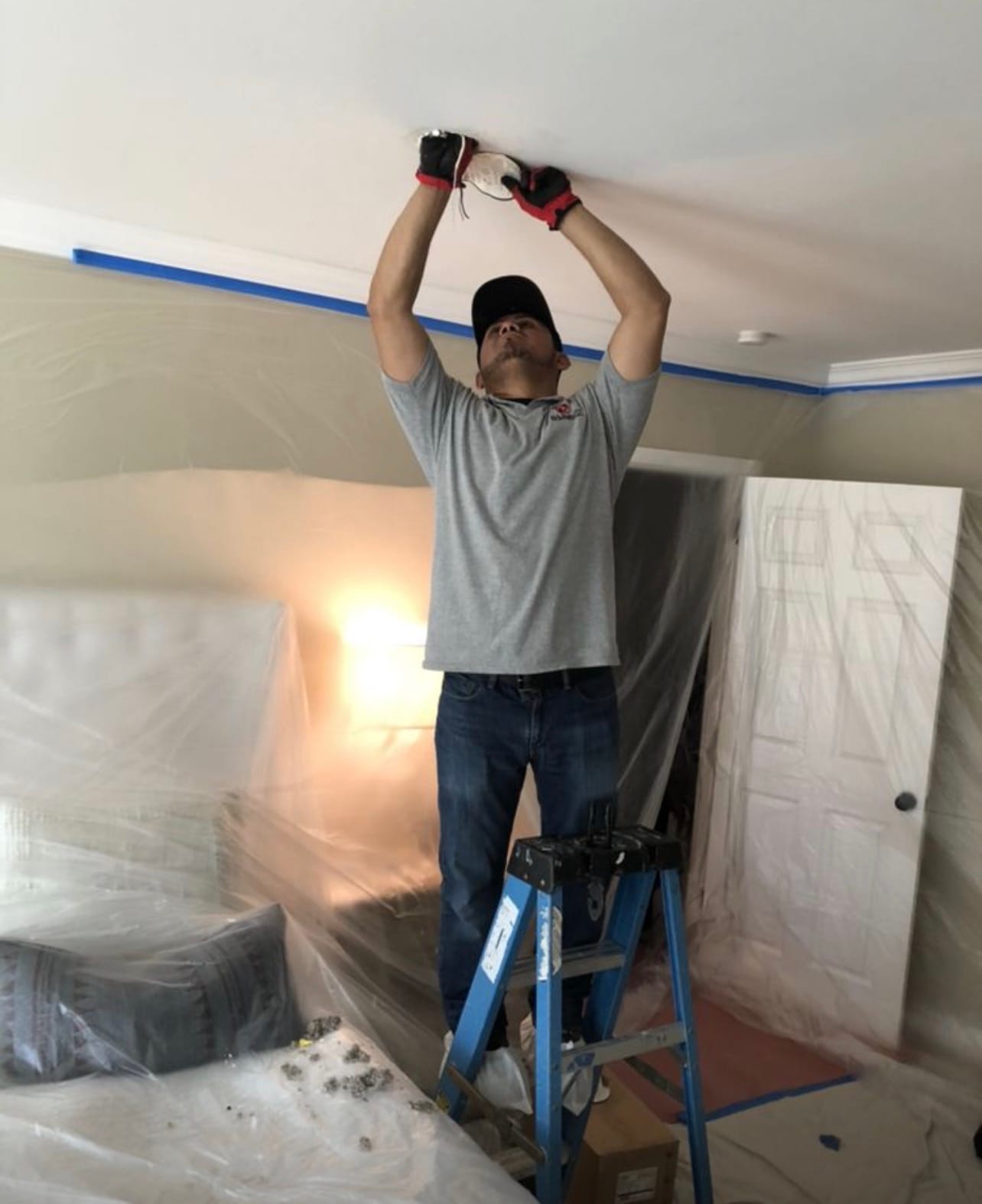 Technician installing a ceiling fixture during a remodel