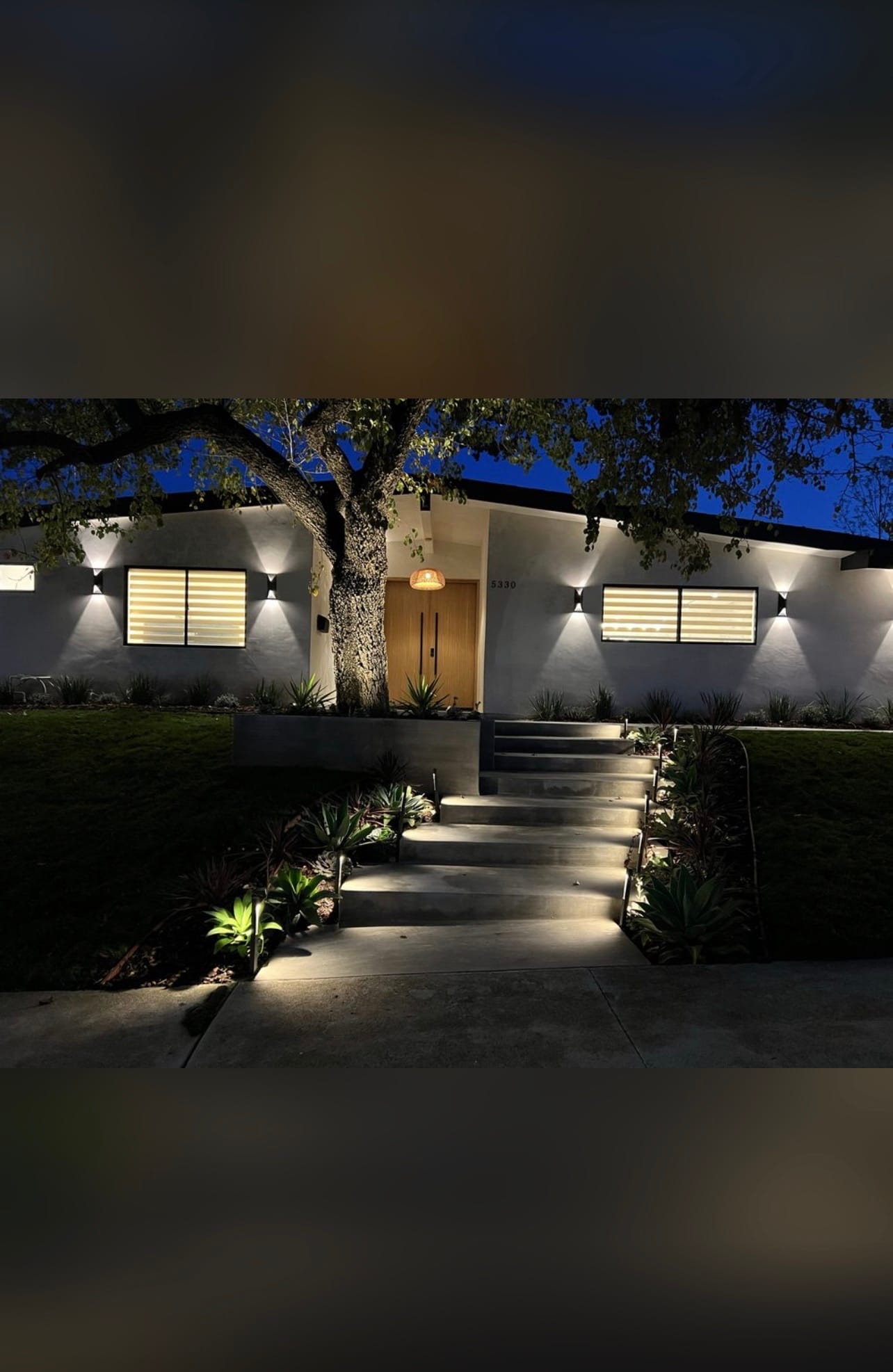 Modern home exterior lit with wall sconces and path lighting